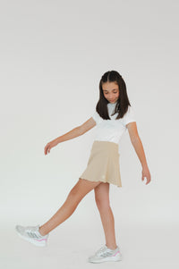  Niña usando falda de golf caqui con lycra elástica - vista lateral en movimiento