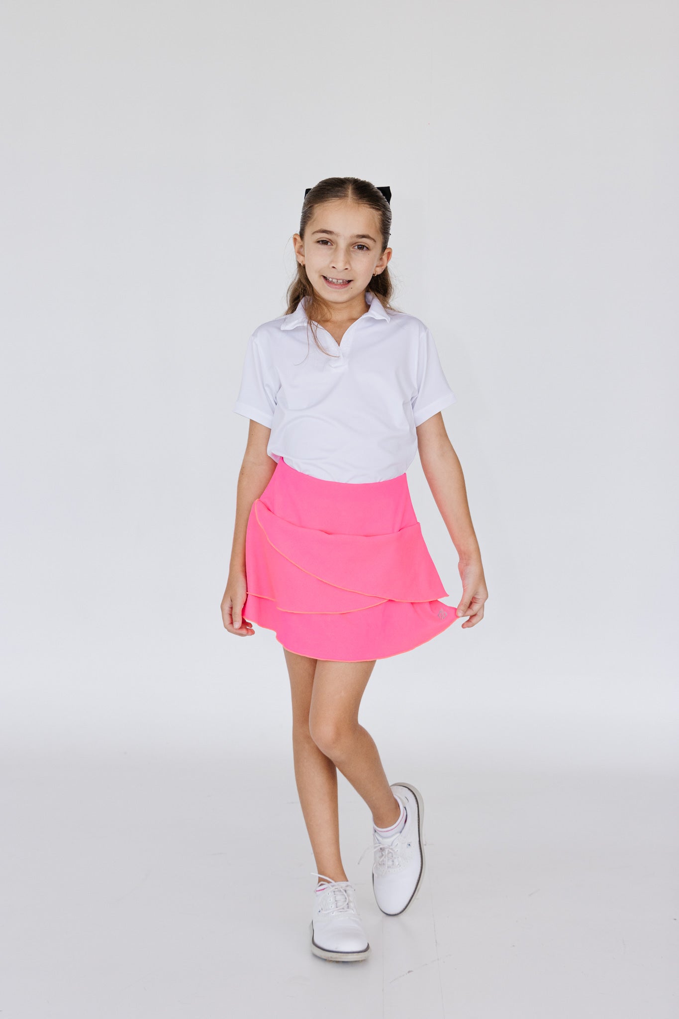 Falda de golf para niña corte tulipán color rosa fosforescente, con lycra dryfit y bolsillo trasero